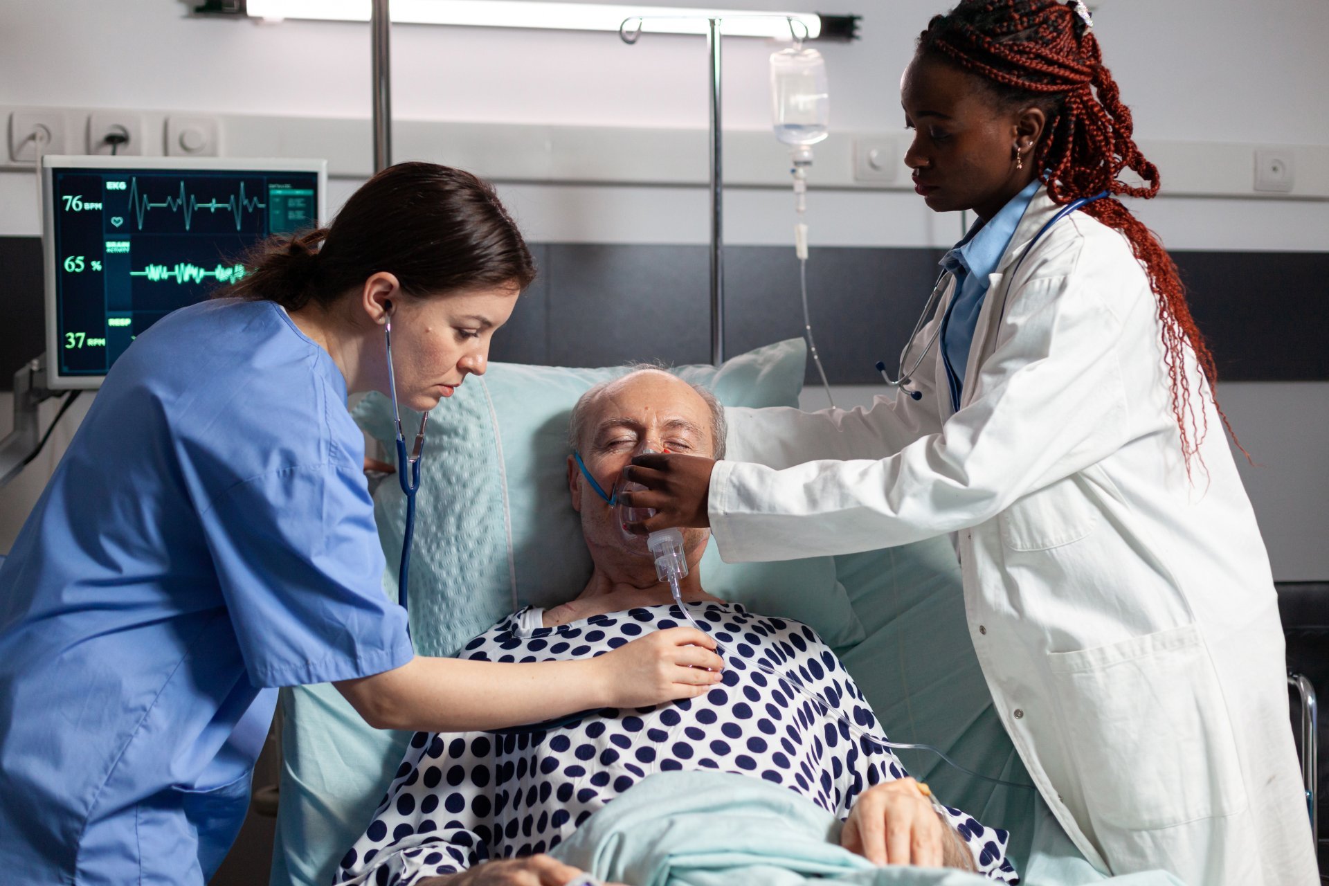 A doctor and nurse help a patient wearing an oxygen mask.