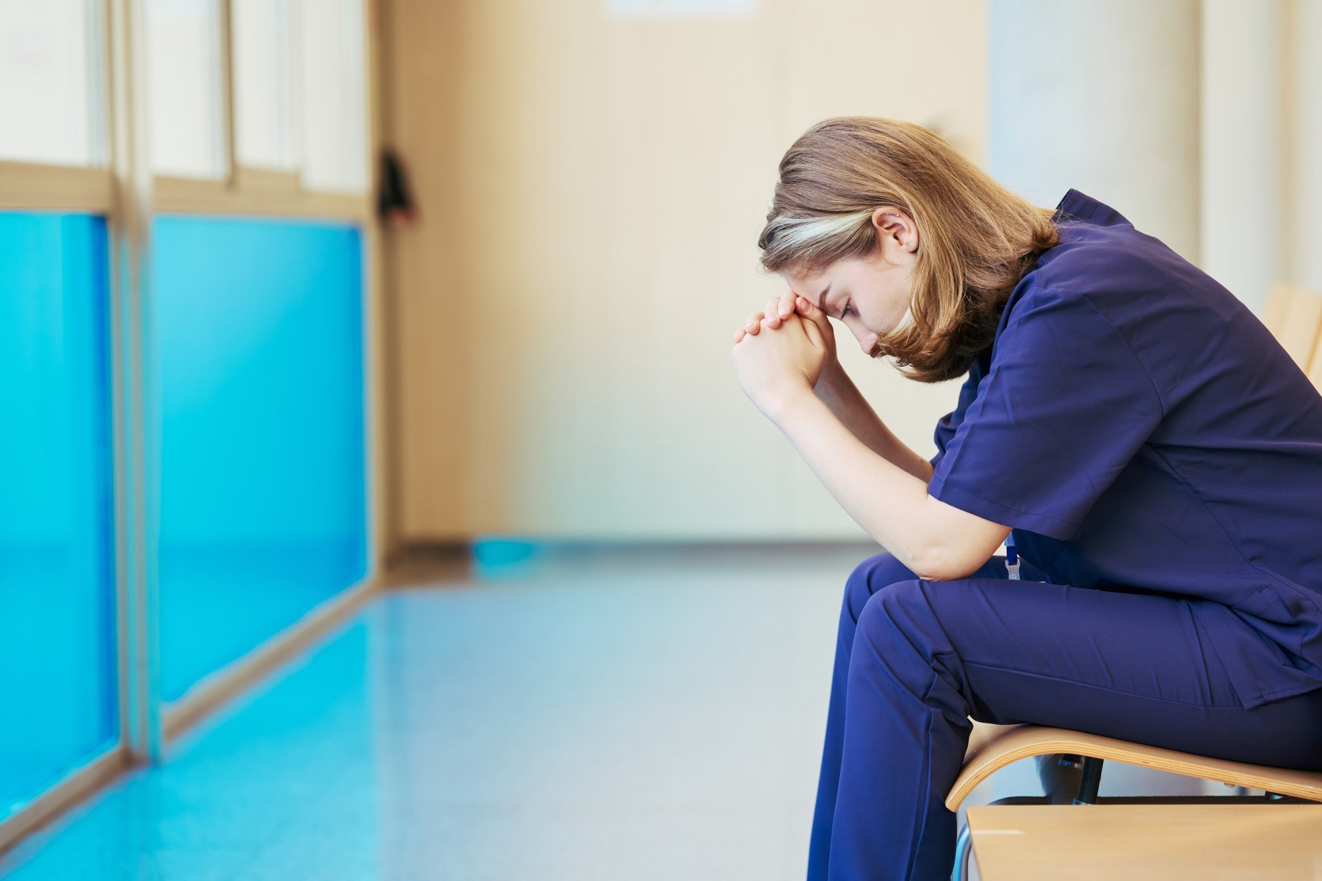 Exhausted nurse feeling stressed sitting in hospital