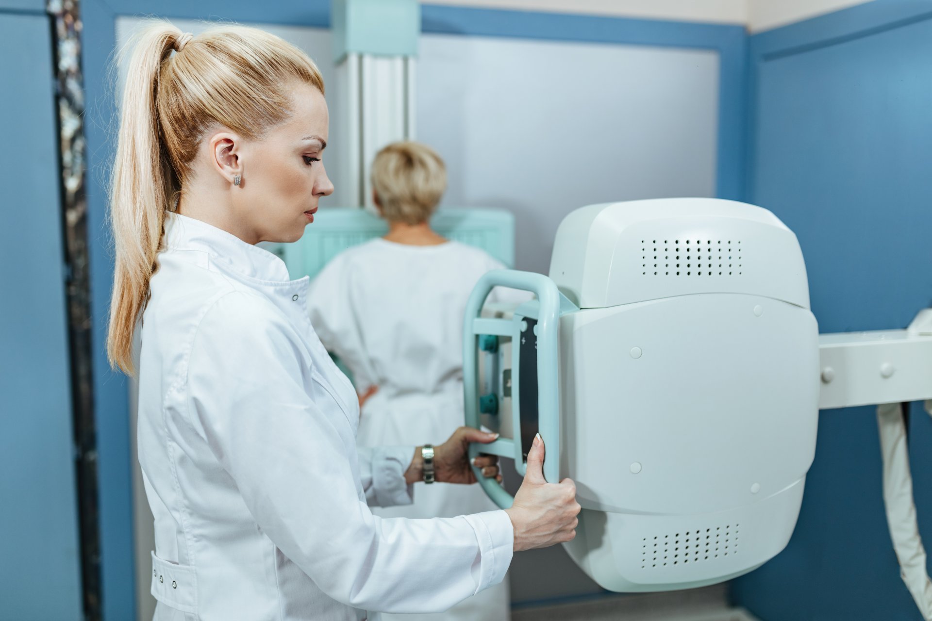 A female radiologic technologist positions an imaging machine.