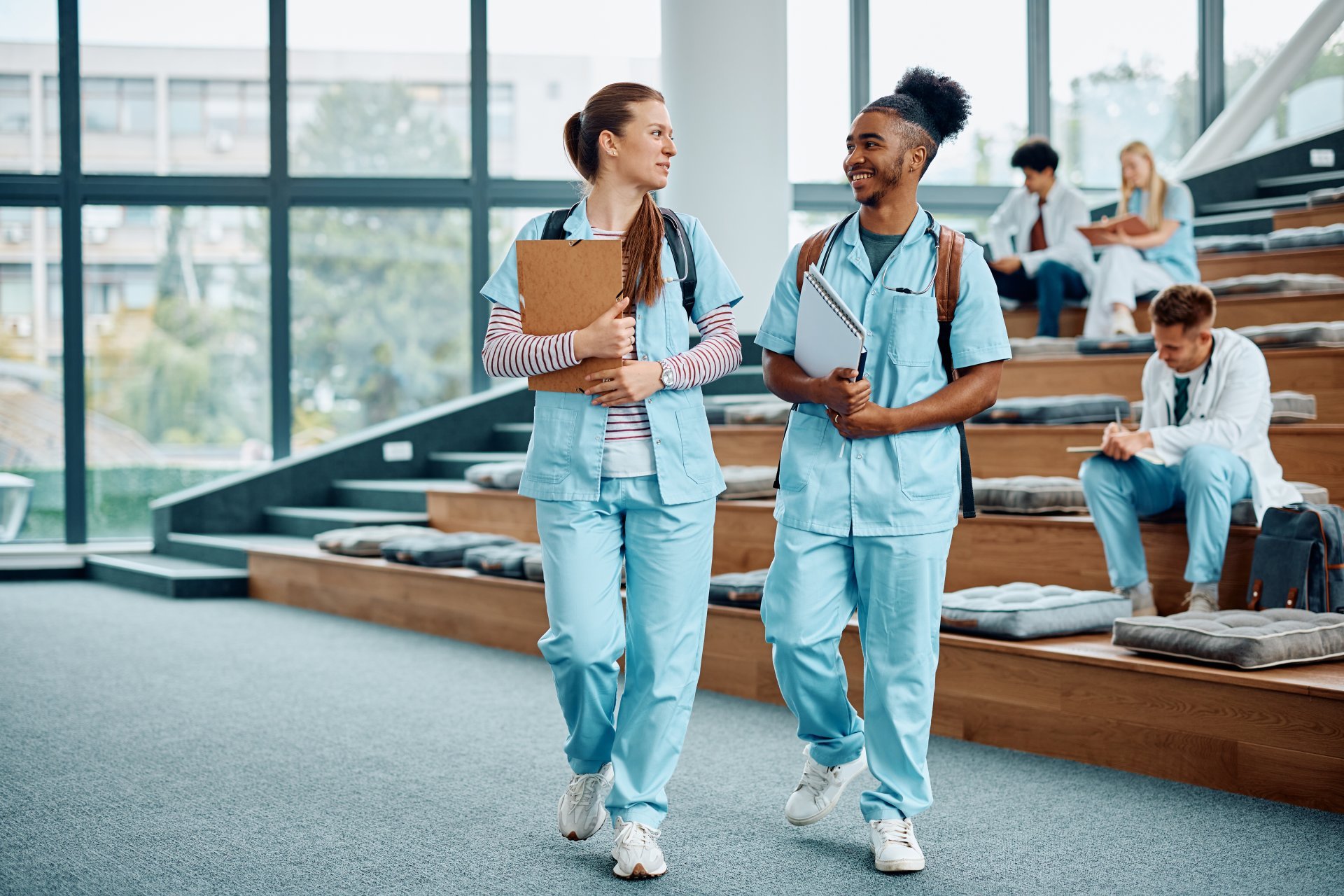 Two nursing students talking in their nursing school classroom.