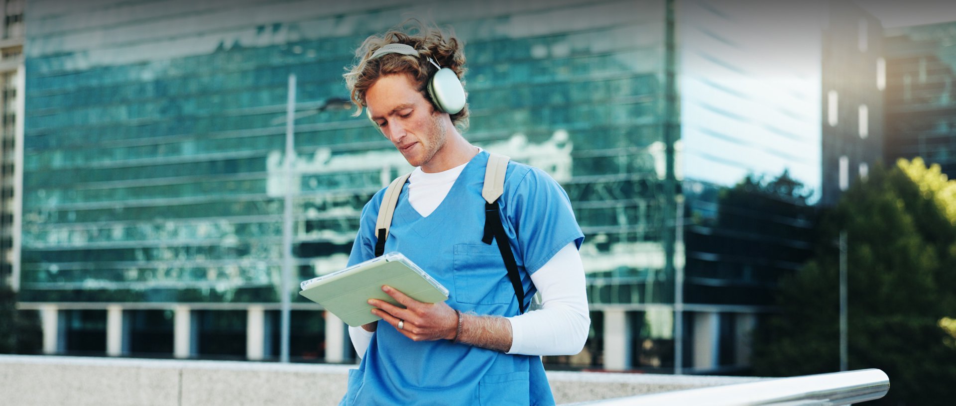 Nurse in headphones walking campus while reading