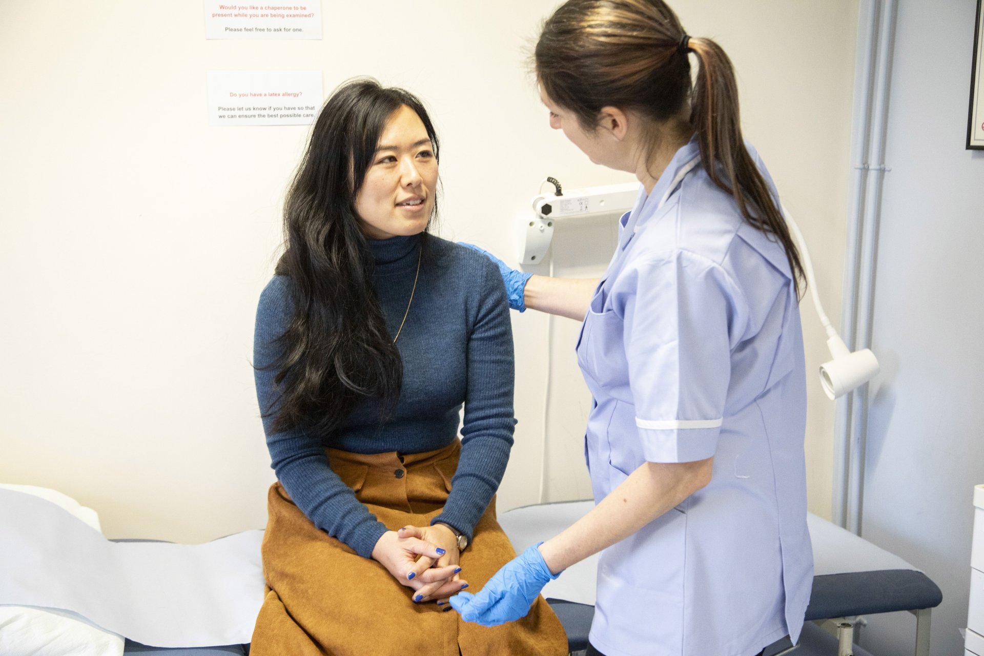 A nurse checking her patient's vitals in a clinical setting.