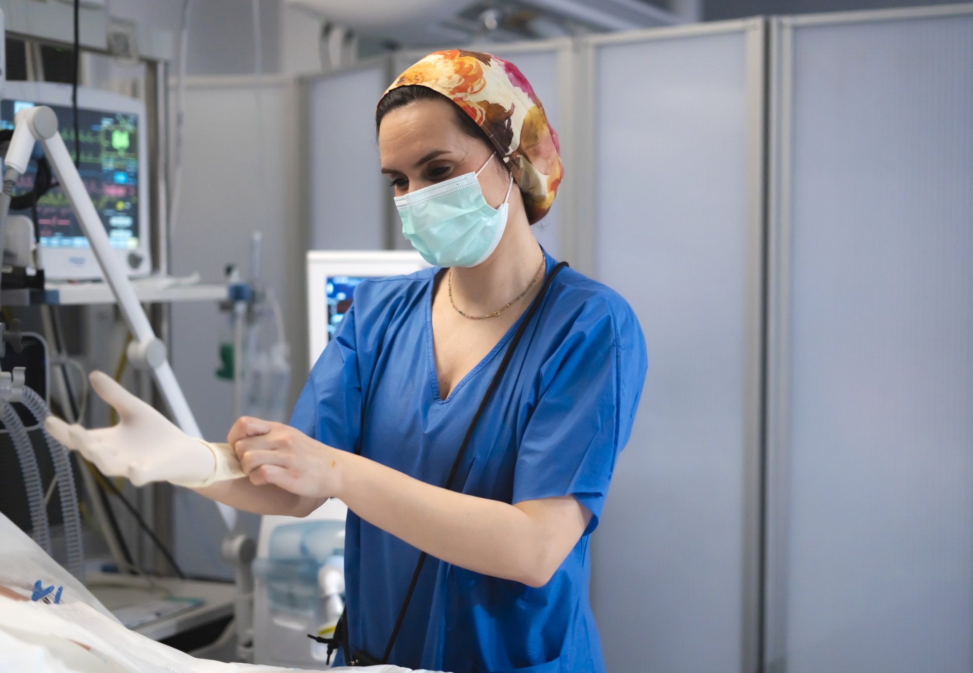 Nurse wearing surgical mask and putting on sterile gloves Nurse wearing surgical mask and putting on sterile gloves