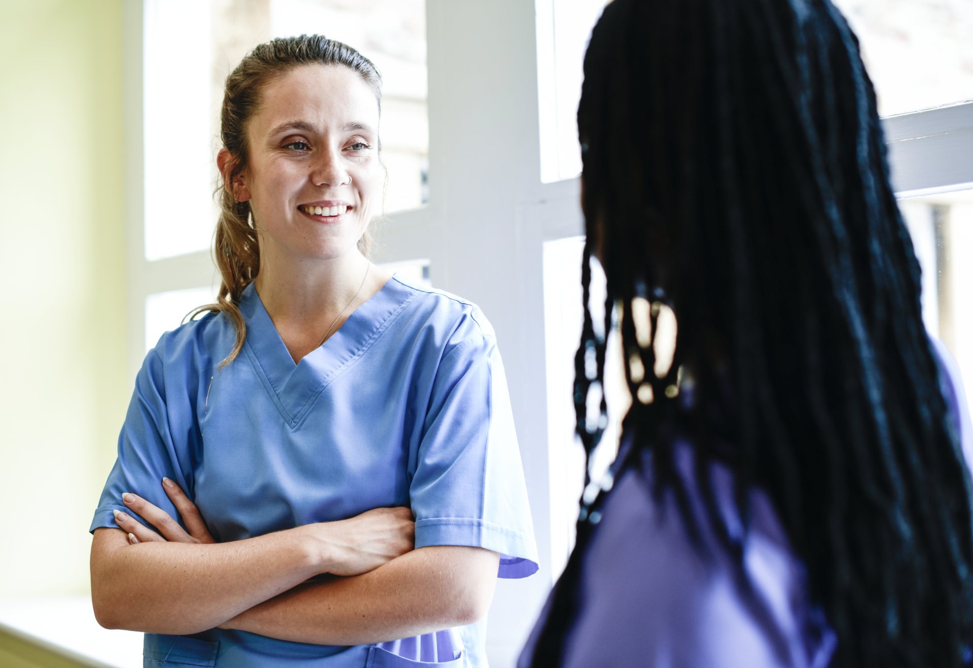 Two female nurses engage in conversation during a break from work.