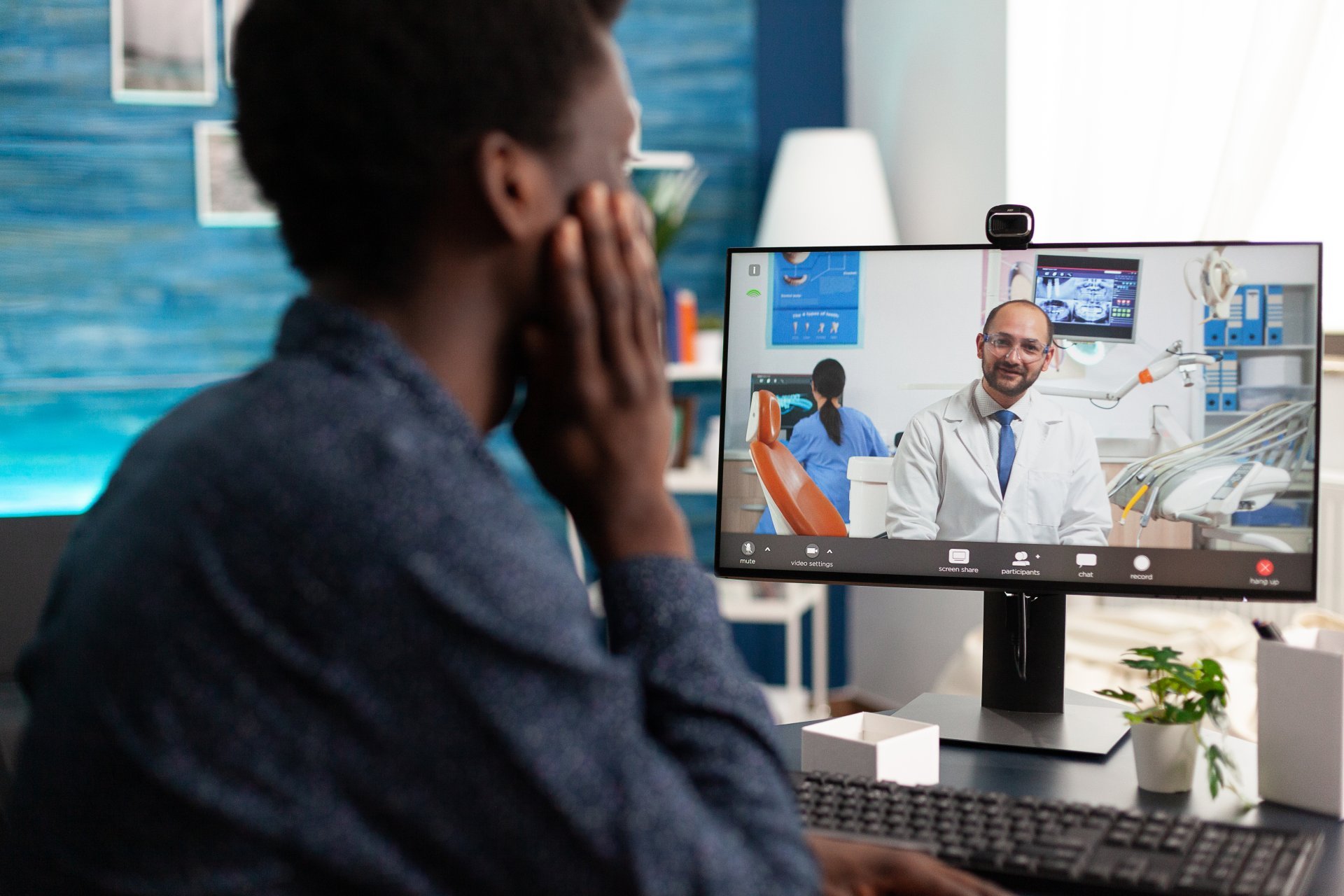 A young man communicates with his doctor during a remote telehealth visit.