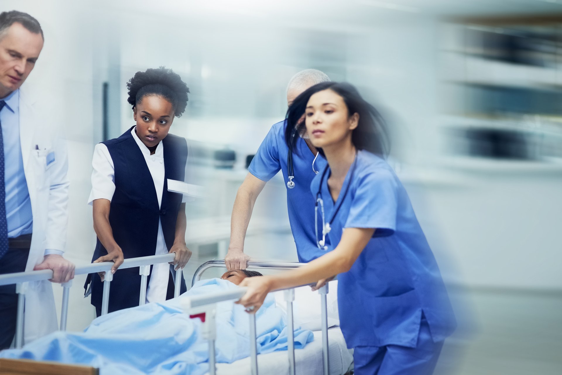 A group of medical professionals rushes a patient in a hospital bed to the operating room.
