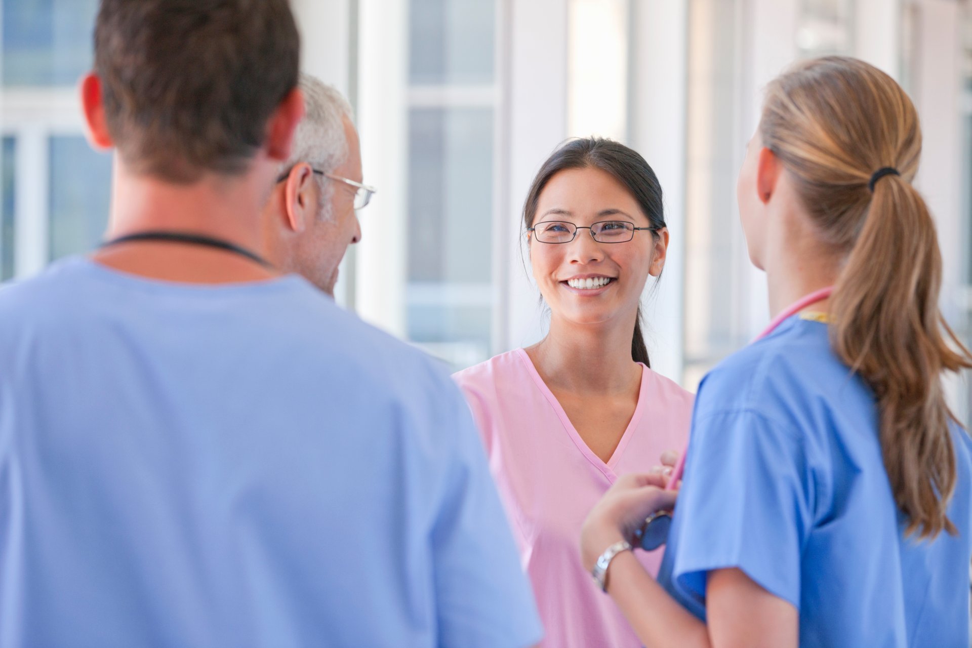 Smiling group of healthcare workers in scrubs talking to each other Smiling group of healthcare workers in scrubs talking to each other