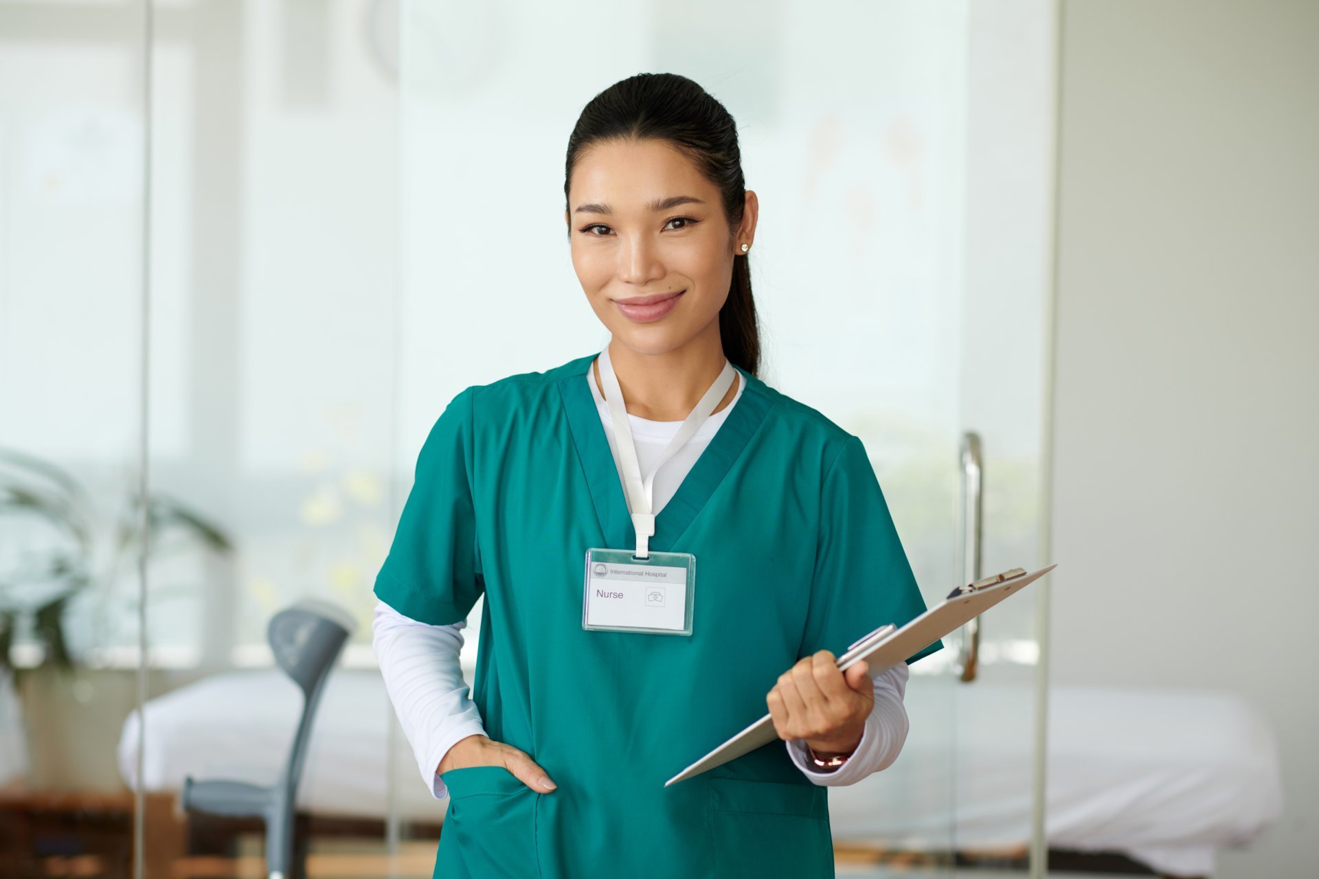 Smiling nurse with scrubs and name badge holding clipboard Smiling nurse with scrubs and name badge holding clipboard