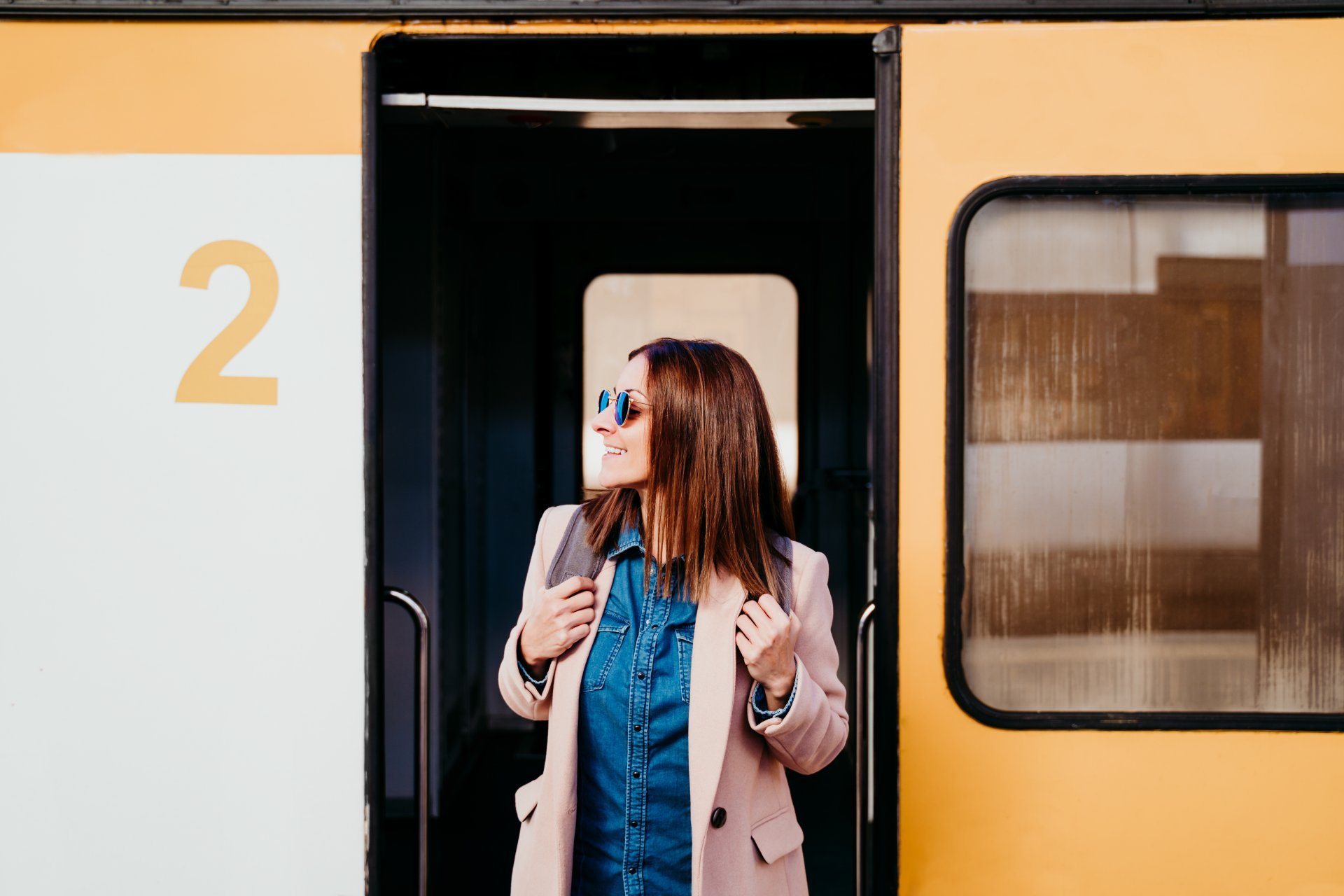 Smiling young woman getting off a train