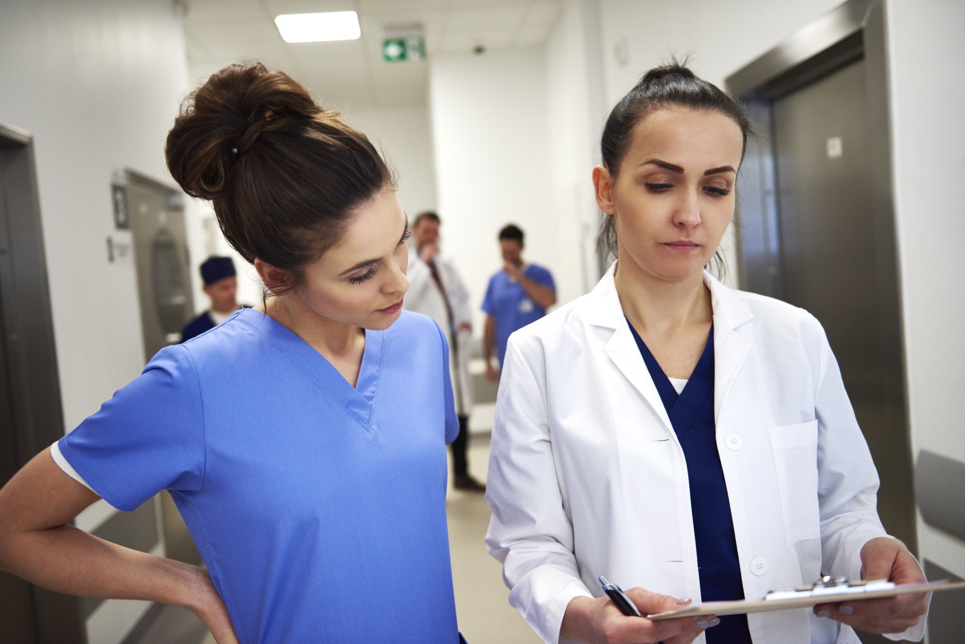 Two busy medical professionals discussing a case near the elevator