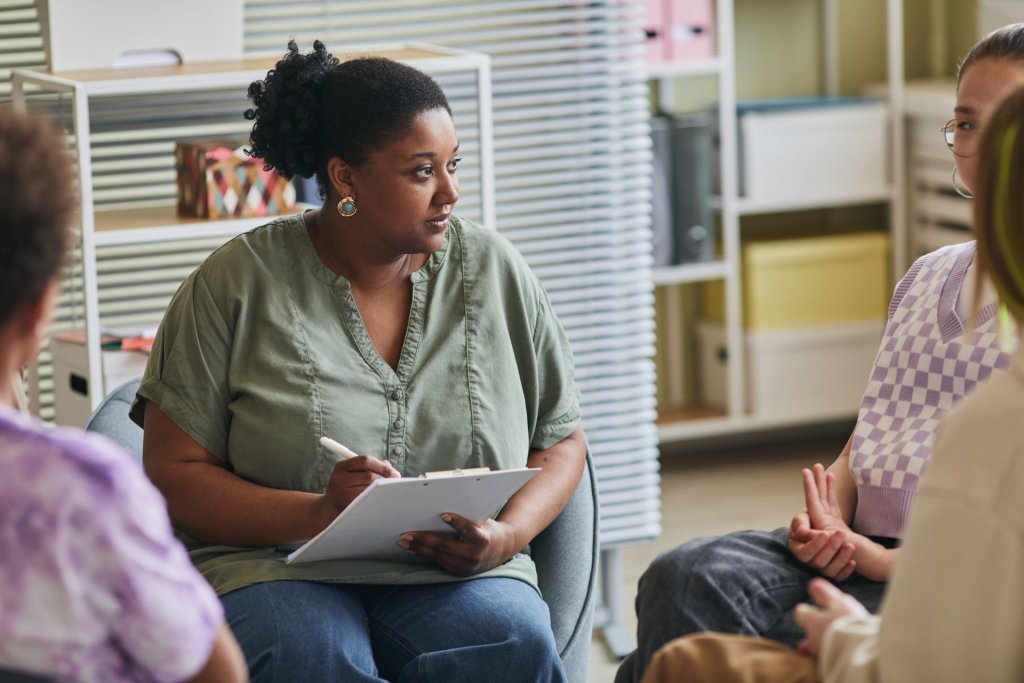 A young female therapist works with a group of young adults.